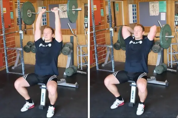 Man utför french press i gym. Han sitter på en bänk med en skivstång över huvudet, redo att sänka den bakom nacken.