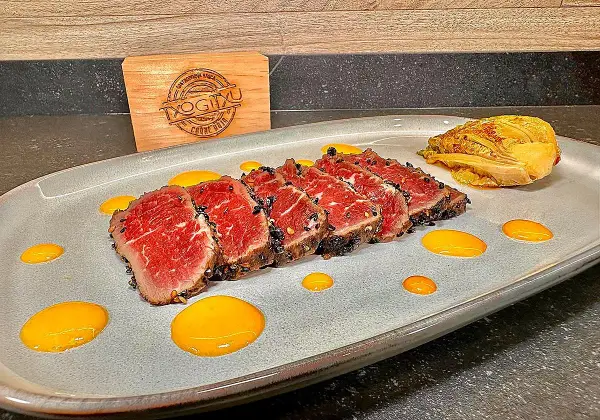 Tataki de ternera con costra de sésamo negro, acompañado de un toque de kimchi y salsa amarilla.