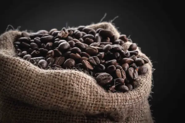 Un saco de arpillera lleno de granos de café tostados, una fuente natural de cafeína para el pelo.