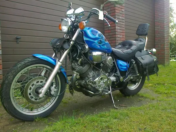 Błękitny motocykl Yamaha Virago 1100 z płomieniami, skórzanymi sakwami i oparciem. Wady i zalety tego klasyka do rozważenia przed zakupem.
