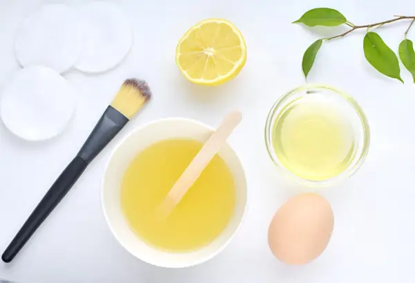 Ingredientes para una mascarilla de huevo para el pelo: huevo, limón, aceite y brocha.