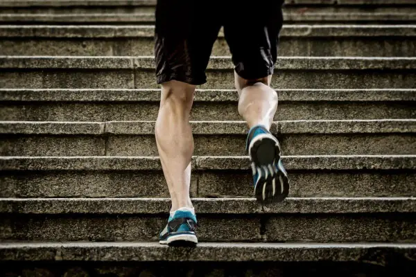 Un homme monte des escaliers, sollicitant ses mollets pour un excellent exercice.