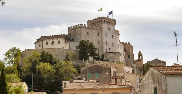 Castello Pasquini domina il paesaggio di Rosignano Marittimo, con le sue torri merlate e le bandiere che sventolano al vento.