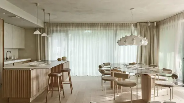 Nowoczesna kuchnia z wyspą i jadalnią. Wnętrze rozświetla designerska lampa wisząca, a całość dopełnia podwieszany sufit.