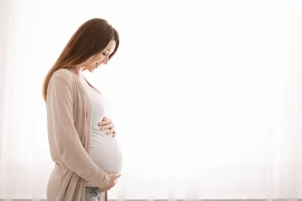 Kobieta w ciąży z hashimoto delikatnie dotyka brzucha, patrząc na niego z miłością.