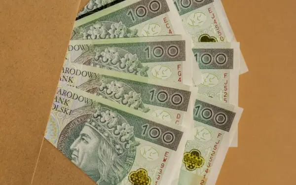Stos banknotów 100 zł, idealnych na prezent, ile daje się na komunię?