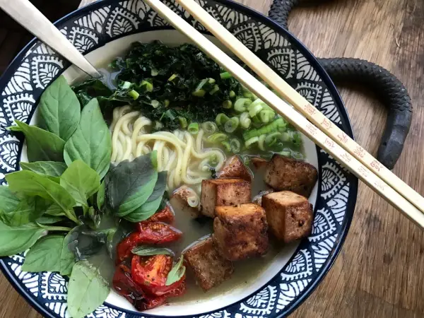 En skål med vegetarisk ramen med nudlar, tofu, grönsaker och basilika.