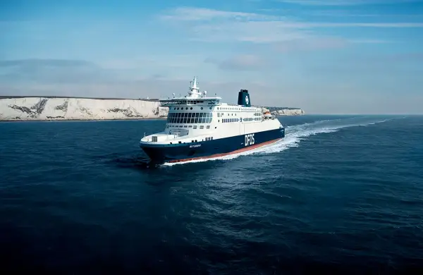 Duży prom DFDS płynie po wzburzonym morzu w kierunku białych klifów. To widok na trasie do Dunkierki.