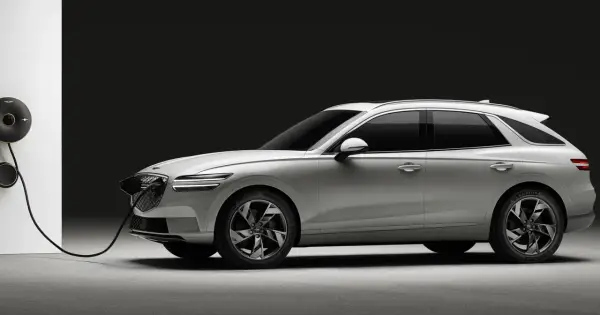 Biały Genesis GV70 na ładowarce. Elegancki SUV z charakterystycznym grillem i światłami LED.