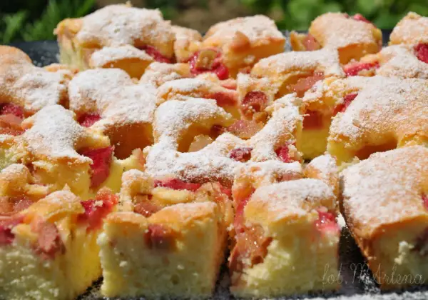 Szybkie ciasto z rabarbarem, posypane cukrem pudrem, wygląda apetycznie. Idealne na letnie popołudnie.