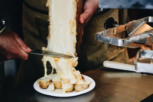 Un morceau de fromage à raclette classique fond sur des pommes de terre. Le fromage dégouline, prêt à être servi.