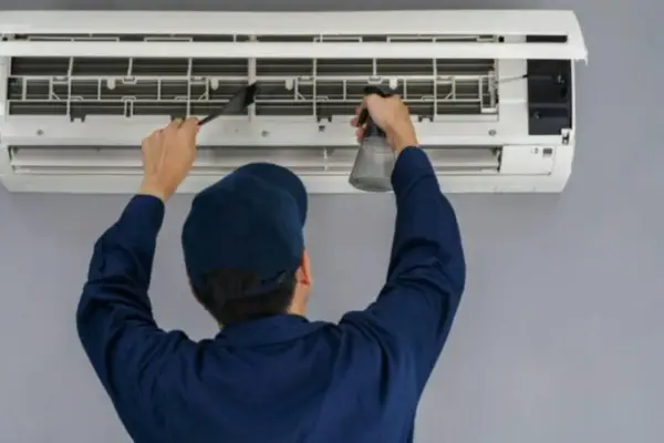 Técnico limpiando un aire acondicionado, paso clave para saber como se instala un aire acondicionado correctamente y mantenerlo.