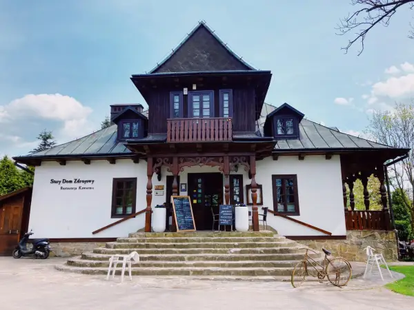 Stary Dom Zdrojowy w Beskidach, z charakterystyczną architekturą i kamiennymi schodami, zaprasza do restauracji.
