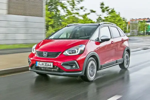 Czerwony Honda Jazz 4 w wersji Crosstar z czarnym dachem i relingami, porusza się po mokrej drodze.