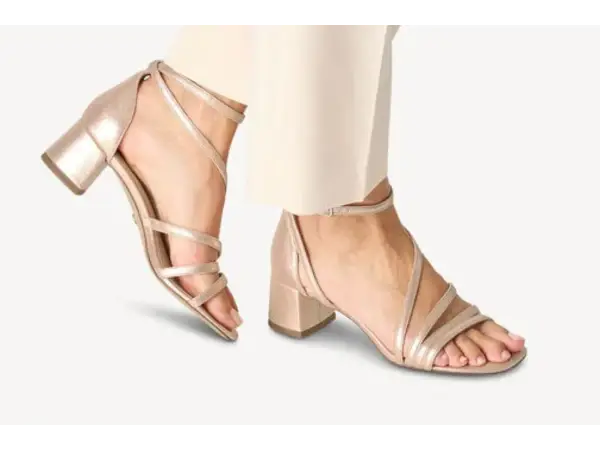 Sandales à talons carrés dorées, avec brides fines croisées sur le pied. Quel vernis avec chaussures dorées ? Un nude ou un rose pâle serait parfait.