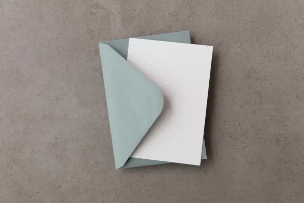 Niebieska koperta z białą kartką. Może symbolizować objawy niedopasowania zaproszenia do charakteru imprezy (mismatch), gdy forma nie odpowiada treści.