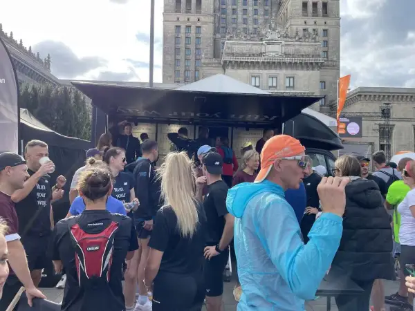 Grupa biegaczy przed budynkiem, dyskutują, czy można biegać codziennie. Na koszulkach napis "Run your way".