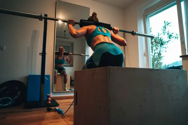 Frau beim Krafttraining für Triathlon, macht Kniebeugen mit Langhantel.