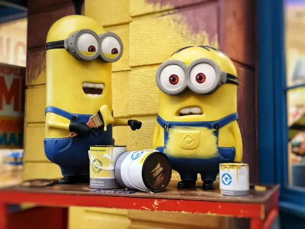 Dwa Minionki malują pędzlem. Jeden z nich ma otwarte usta, drugi wygląda na zaskoczonego. To inspiracja, jak zrobić strój Minionka!