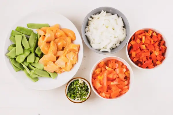 Ingredientes para fideuá de pollo: trozos de pollo, judías verdes, cebolla, pimiento rojo, tomate y perejil picado.