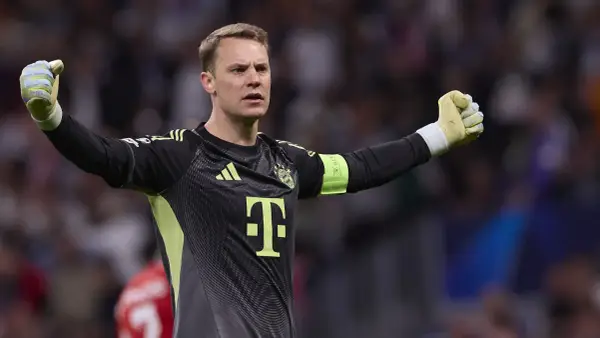 Bramkarz Bayernu Monachium, Manuel Neuer, w akcji. Jego ręce są uniesione, gotowy do obrony.