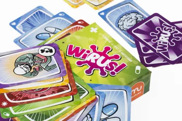 Kolorowe karty do gry "Wirus!" przedstawiają elementy medyczne i wirusy. Na jednej z kart widać postać wstrzykującą sobie coś z strzykawki.