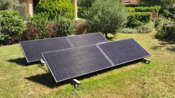 Panneaux solaires sur pelouse, promesse de rentabilité panneau solaire autoconsommation. Jardin verdoyant, maison en arrière-plan.