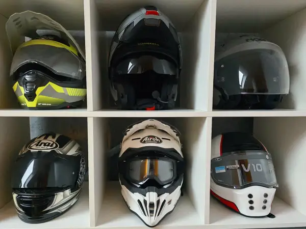 Sześć kasków motocyklowych w różnych kolorach i stylach, ułożonych w sześciu przegrodach.