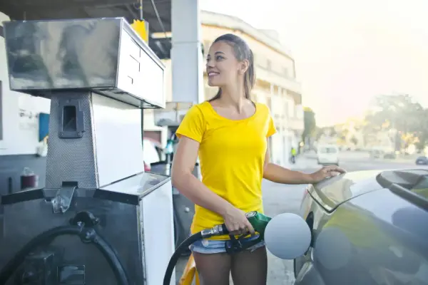 Uśmiechnięta dziewczyna tankuje auto, nalewając Vervę 98.