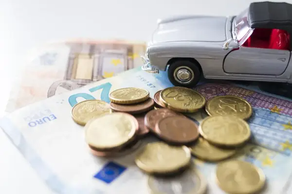Modellino d'auto su banconote e monete euro. Un promemoria dei costi di gestione, incluso il **super bollo auto**.