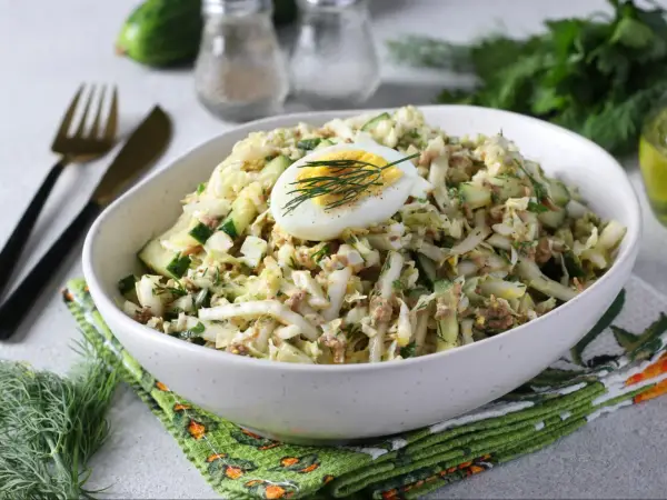 Lekka sałatka z tuńczykiem, jajkiem i ogórkiem, udekorowana koperkiem. Idealna na szybki lunch.