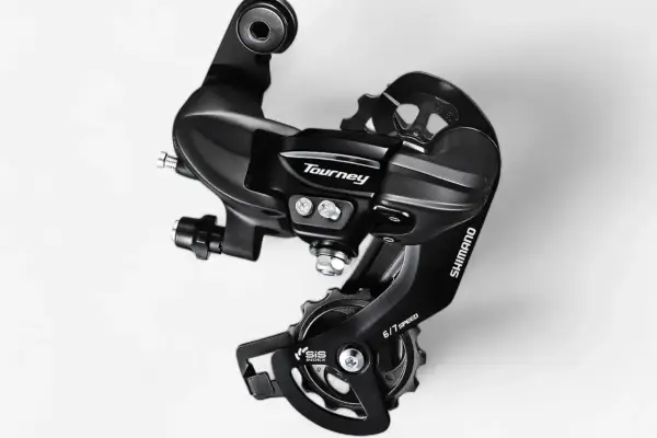 Czarny, tylny przerzutka Shimano Tourney SIS 6/7 Speed. Dowiedz się, jak zmieniać przerzutki w rowerze szosowym, by jazda była płynniejsza.