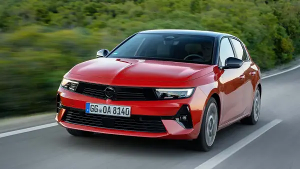 El nuevo Opel Astra rojo, con techo negro, circula por una carretera sinuosa rodeada de vegetación.