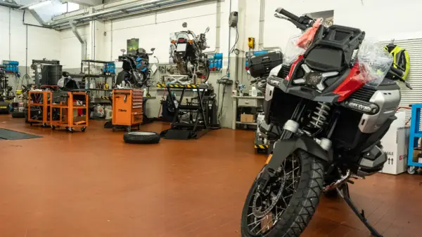 Officina moto con diverse moto in lavorazione. Un tecnico si chiede ogni quanto si fa il tagliando per mantenere al meglio il proprio mezzo.