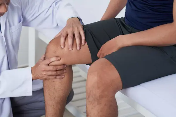 Fizjoterapeuta bada kolano pacjenta, sugerując ćwiczenia na chondromalację rzepki.