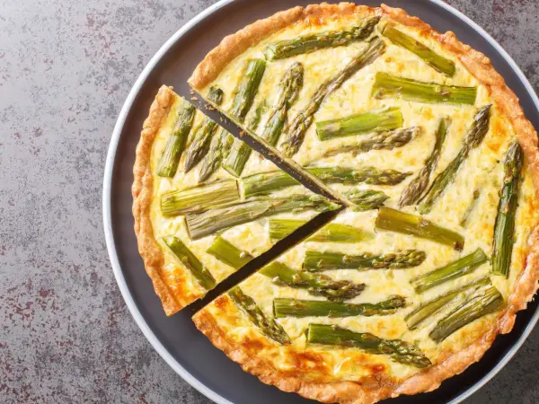 Eine köstliche Spargel Quiche mit einem goldbraunen Teigrand und saftiger Füllung, belegt mit frischem Spargel.