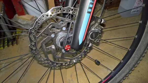 Hamulec tarczowy roweru z mocowaniem **center lock**. Widoczna tarcza hamulcowa Shimano, zacisk i szybkozamykacz DT Swiss.