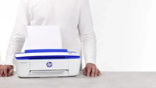 Biała drukarka HP DeskJet 3790 z niebieskimi elementami, z papierem w podajniku. Ułatwia drukowanie, gdy masz instrukcję pod ręką.