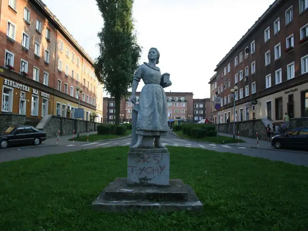 Pomnik w stylu socrealizmu na tle bloków mieszkalnych.