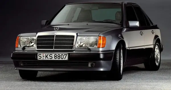 Klasyczny youngtimer, szary Mercedes-Benz W124 z charakterystyczną kratką i reflektorami.