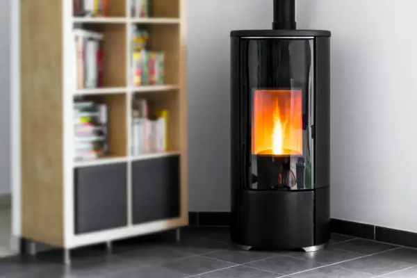Stufa a pellet moderna in camera da letto, con fiamme vive che illuminano l'ambiente. Accanto, una libreria in legno con libri.