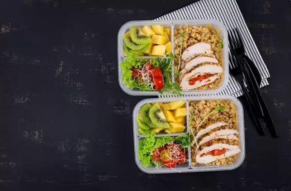 Dwa pudełka na lunch do pracy: kurczak faszerowany, kasza, sałatka z pomidorkami i kiełkami, kiwi i mango.
