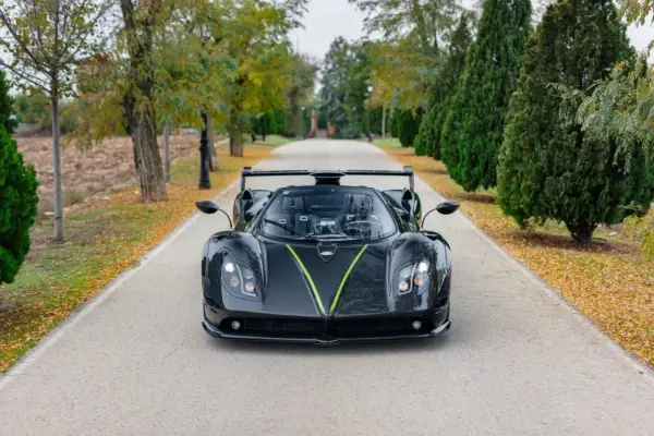 Czarny Pagani Zonda z zielonym akcentem na masce, zaparkowany na alei. Jego cena jest astronomiczna.