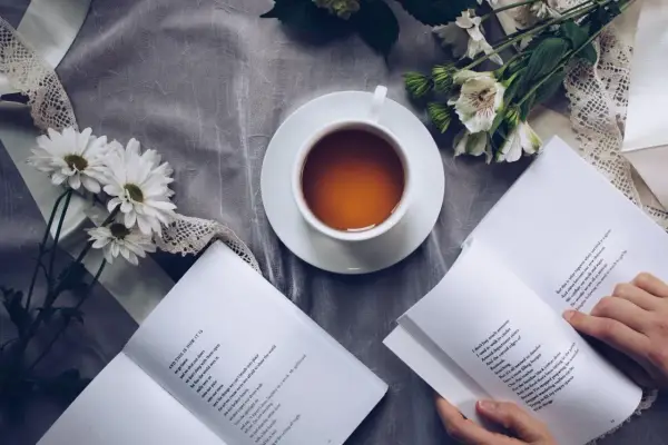 Eine Tasse Tee, Blumen und ein Buch mit einem wehmütigen Gedicht.