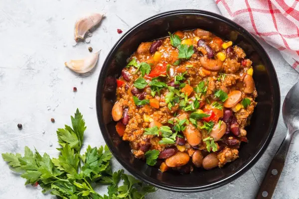 Un bol de chili sin carne, garni de persil frais. Des haricots rouges, du maïs et des dés de poivrons se mêlent à la viande hachée dans cette recette réconfortante.