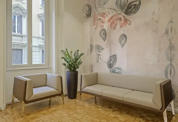 Eleganckie fotele i sofa na tle tapety z motywem kwiatowym. Czy można kleić tapetę na tapetę? Tutaj wygląda to stylowo.
