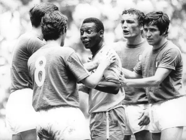Słynny piłkarz brazylijski, Pelé, otoczony przez innych graczy, w geście sportowego szacunku po meczu.