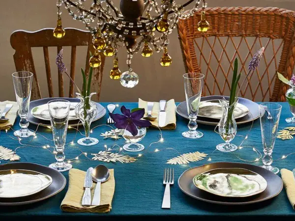 Une table dressée avec élégance, des verres étincelants et des fleurs délicates. L'art de la table est célébré sous un lustre scintillant.
