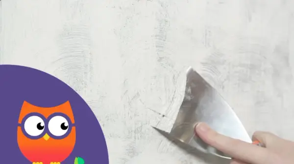 Maintenant, il faut enlever la peinture d'un mur avec une spatule. Un hibou curieux observe.