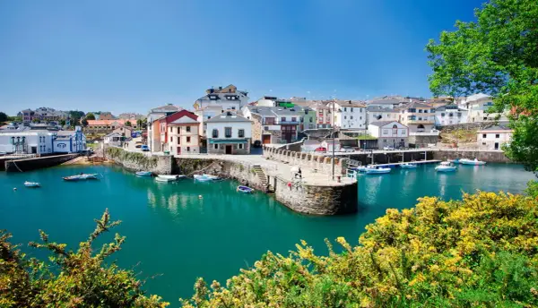 El pintoresco puerto vega, con sus casas coloridas y barcos meciéndose en aguas turquesas, bajo un cielo azul.